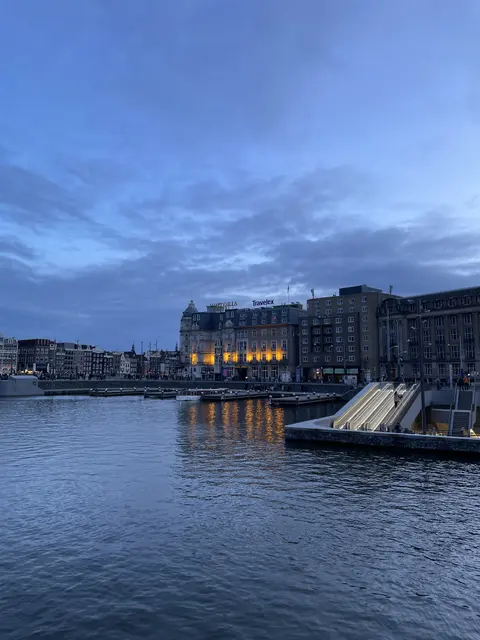 Waterfront buildings beneath a blue evening sky.