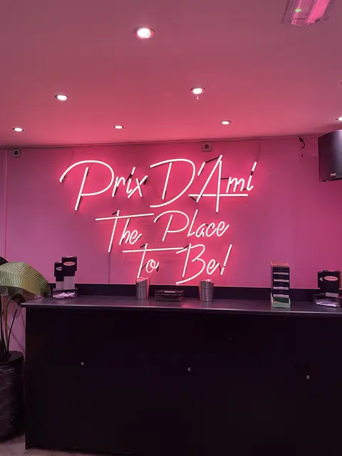 A pink neon sign above an indoor counter.