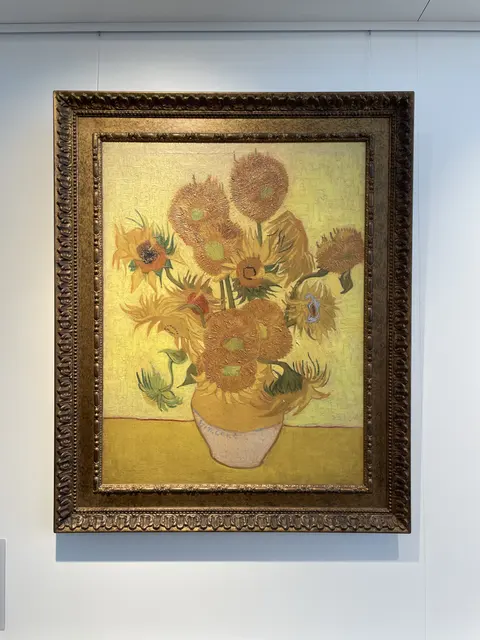 A framed painting of sunflowers in a vase.