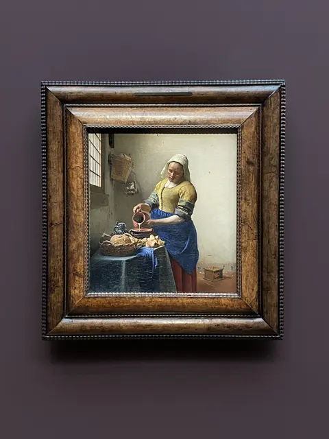 A framed painting of a woman pouring milk.