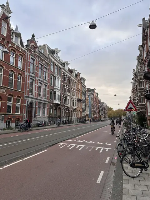 A broad street lined with tall brick buildings and bicycles.