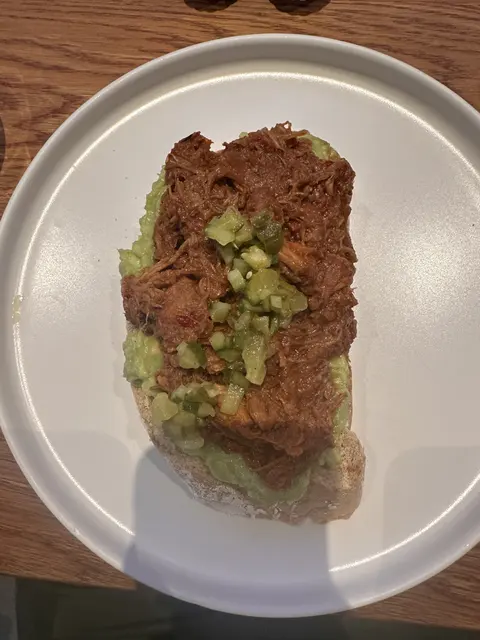Toast topped with chopped greens on a white plate.