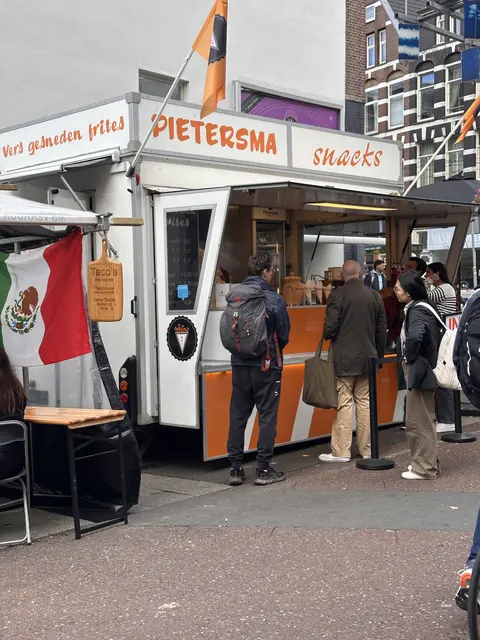A small food stall with customers outside.