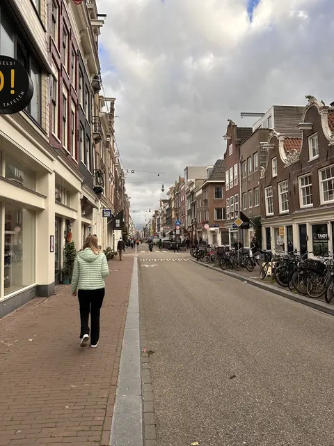 A pedestrian on a street lined with narrow brick buildings.