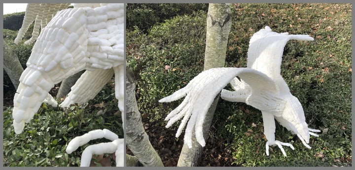 White sculptural birds suspended above a green landscape.