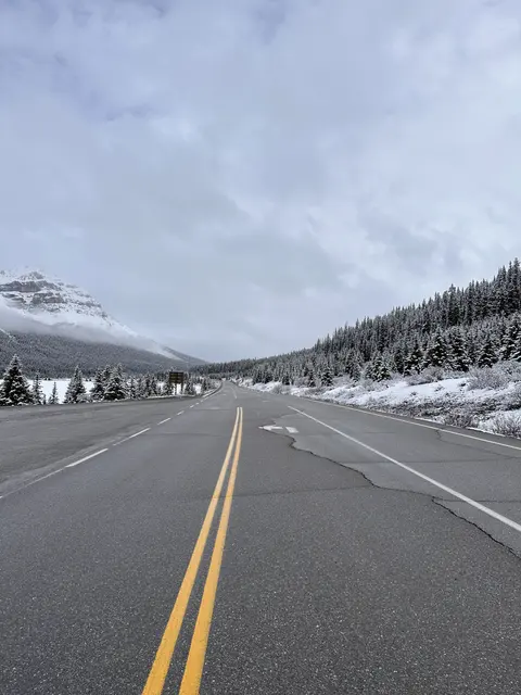 An empty road leading toward snow-covered mountains.