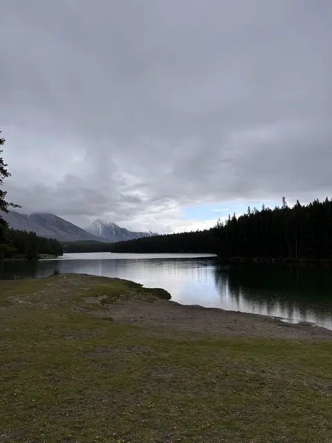 A quiet lakeshore bordered by forest and mountains.