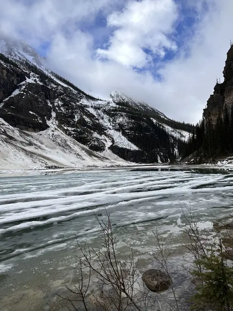 Snow-covered mountains above a partly frozen lake.