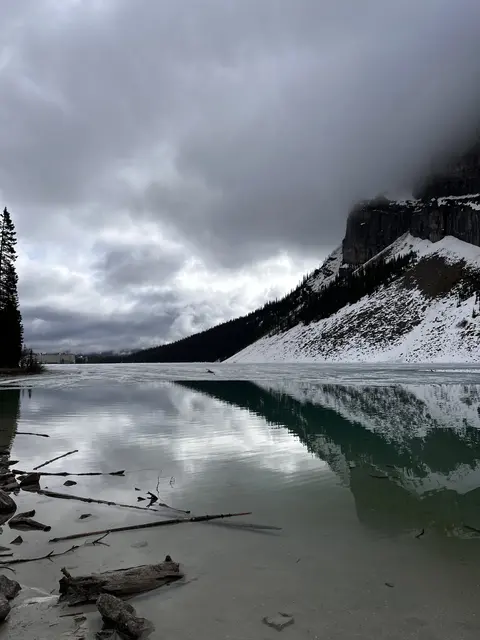 A mountain reflected in turquoise water beneath heavy clouds.