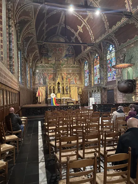 Rows of wooden chairs inside an ornately decorated chapel.