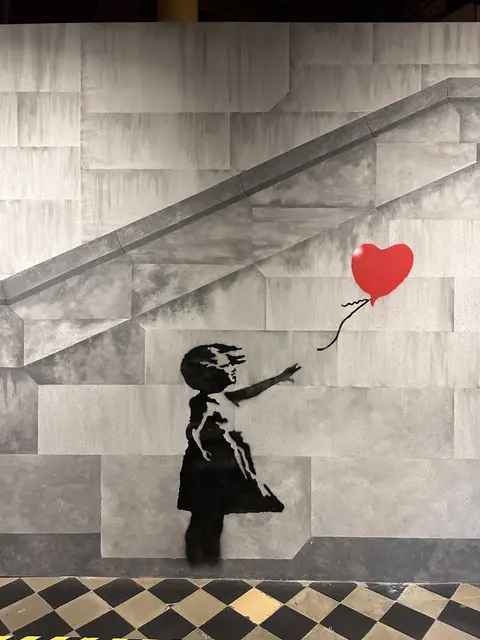 A mural of a girl reaching toward a red heart-shaped balloon.