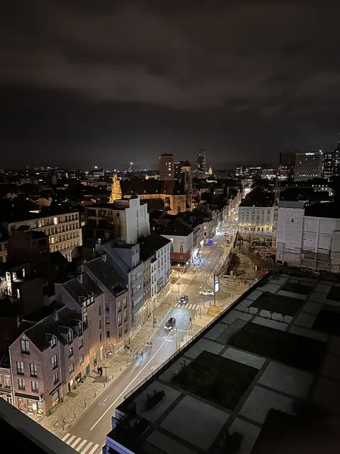 An elevated nighttime view over city rooftops and streets.