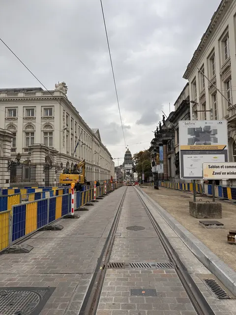 Tram tracks running down a city street beneath grey clouds.
