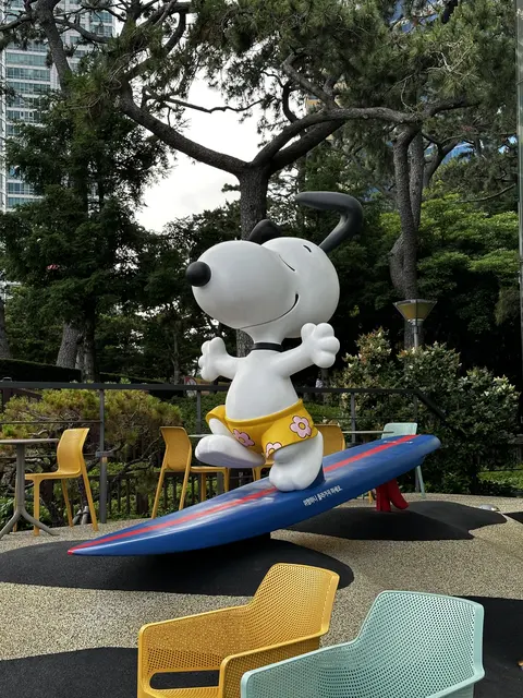 A cartoon figure on a colorful seesaw in a leafy garden.