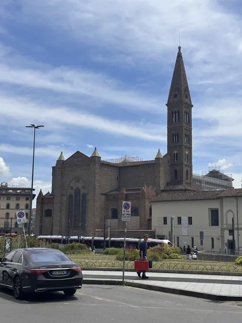 A church and slender bell tower beside a city street.