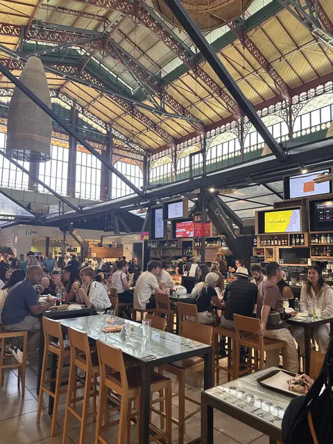 Diners gathered beneath the metal roof of a busy indoor market.