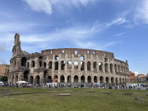 The exterior of the Colosseum beneath a blue sky.