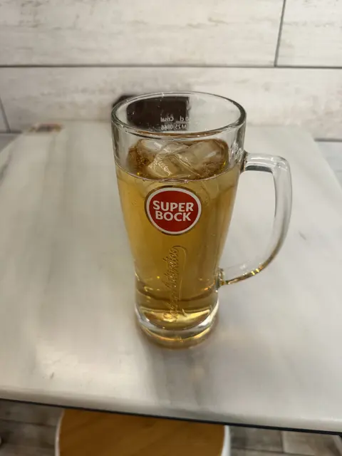 A glass mug of beer on a white tabletop.