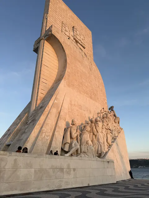 A tall stone monument with carved figures beneath blue sky.