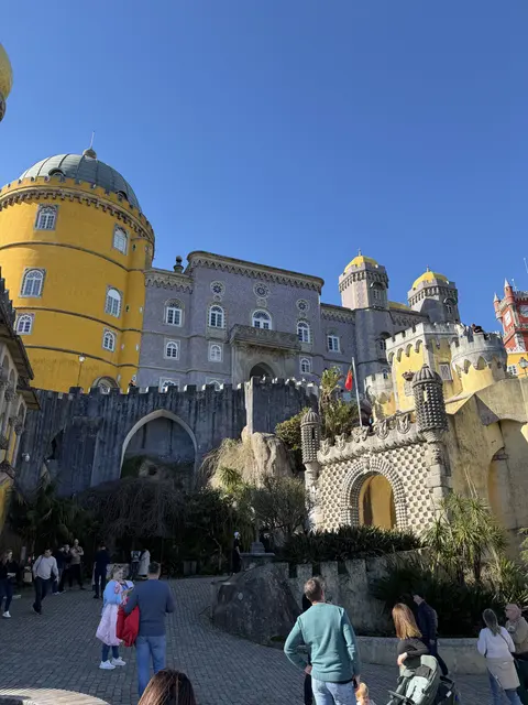 A colorful palace with yellow towers and arched terraces.