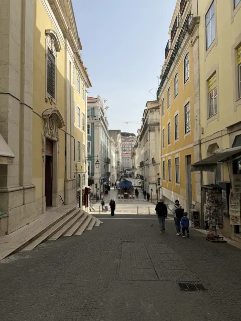 A narrow street descending between yellow buildings.