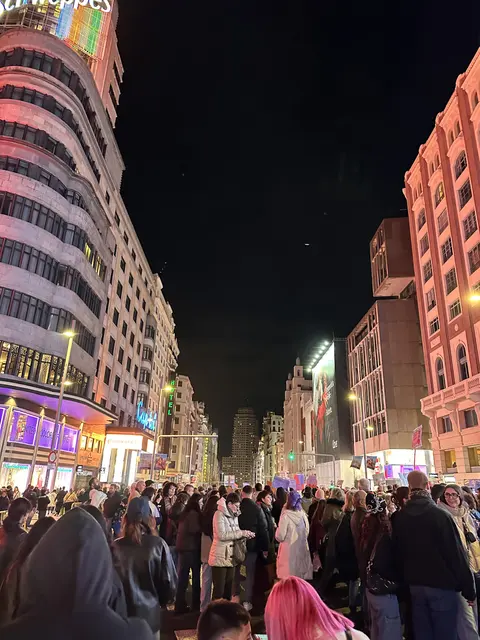 Crowds on a brightly illuminated city street at night.