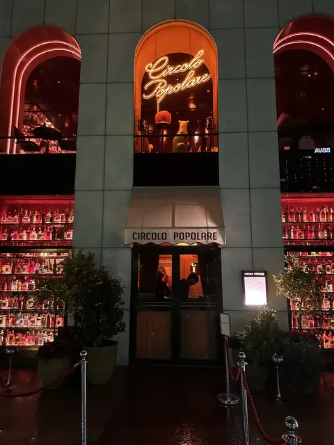 A restaurant entrance beneath glowing red and orange signs.