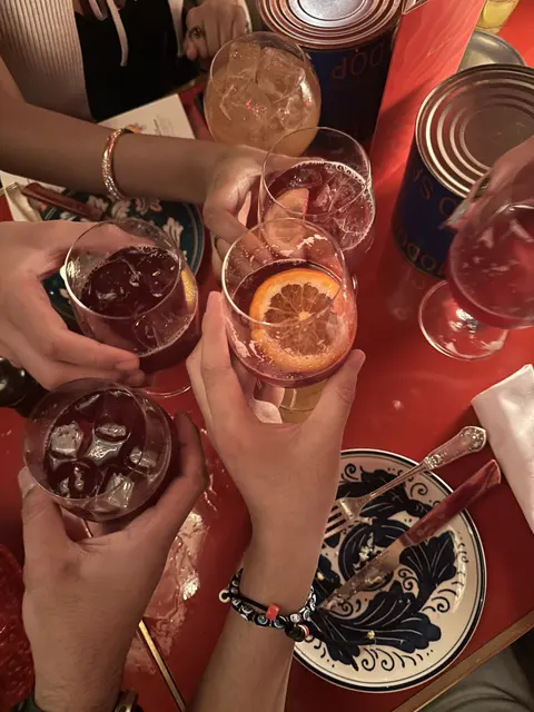 Hands holding drinks above a restaurant table.