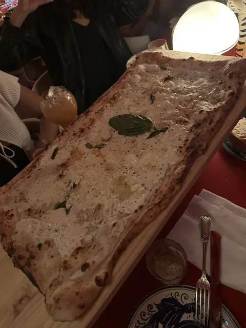 A long rectangular pizza topped with herbs and cheese.
