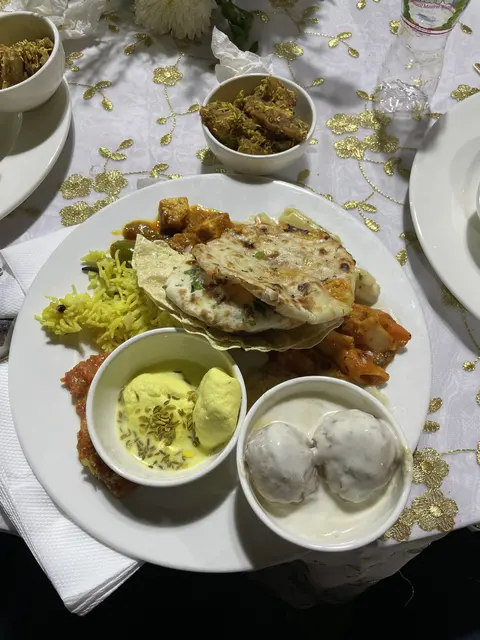 A meal with flatbread, curries, rice, and side dishes.