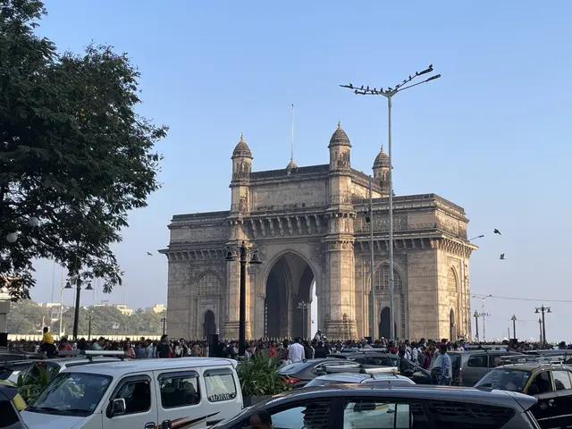 A monumental stone arch with traffic and crowds in front.
