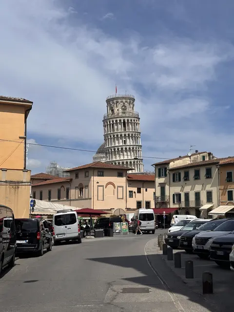 The Leaning Tower seen beyond a street and parked cars.