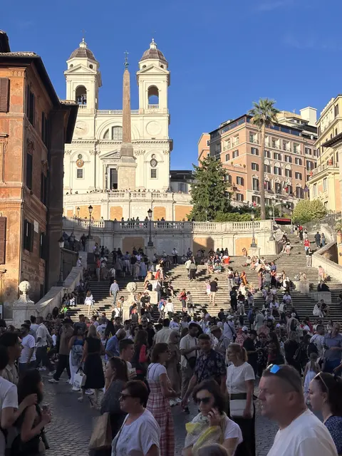 A crowded staircase leading up to a twin-towered church.