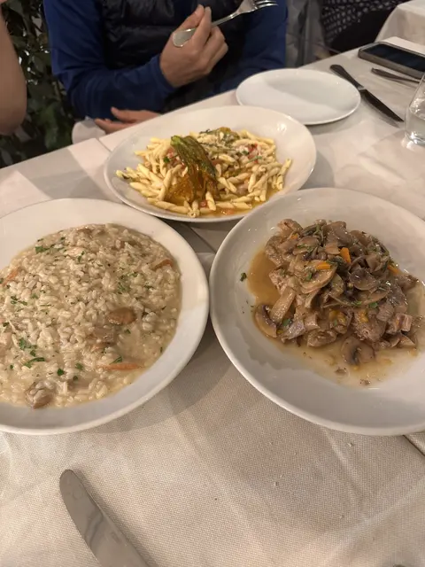 Three plates of pasta on a white tablecloth.