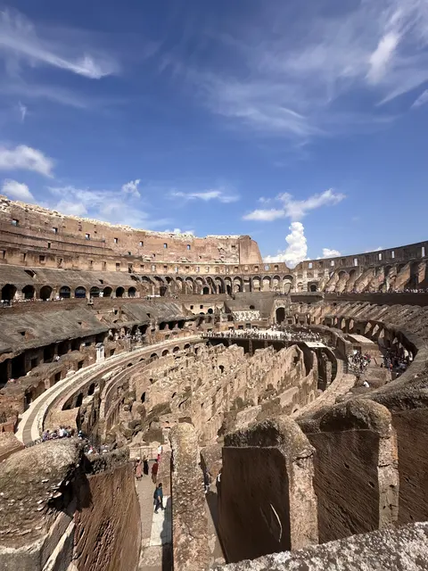 The interior of an ancient amphitheater beneath blue sky.