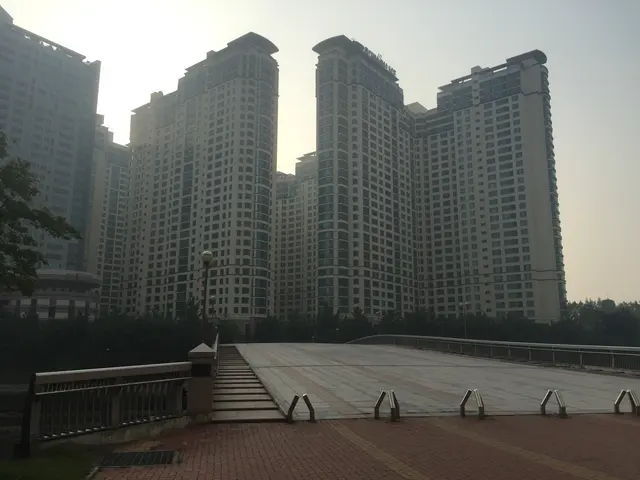 High-rise apartment buildings beside a paved riverside area.