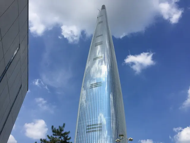 A tall glass skyscraper rising into a blue sky.
