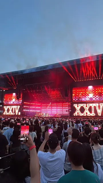 A concert crowd facing a stage lit in red.