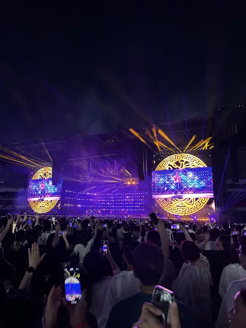 A concert stage glowing purple and yellow at night.