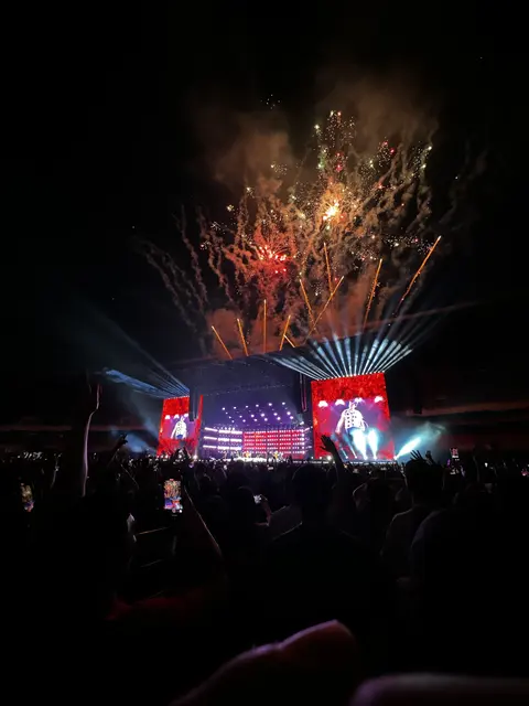 Fireworks above a brightly illuminated concert stage.
