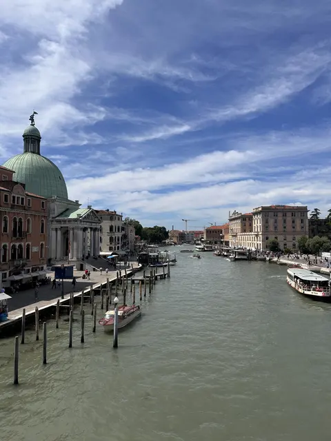 A broad canal with domed buildings beneath streaks of cloud.