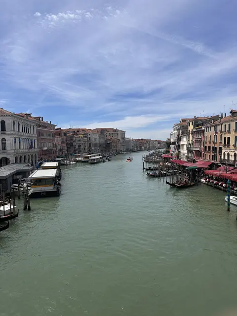 Boats traveling along a broad canal beside historic buildings.
