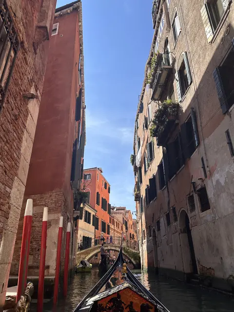 A gondola passing between tall buildings on a narrow canal.