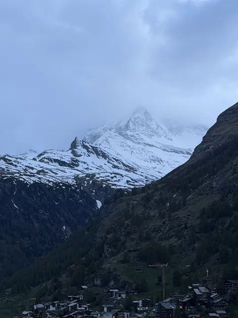 A snow-covered mountain peak emerges through low blue clouds.