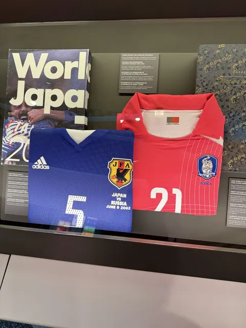 Japan and South Korea football shirts displayed behind glass.